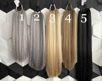 Può includere: Cinque extensioni per capelli di diversi colori con i numeri da 1 a 5 etichettati su di esse. Le extensioni sono tutte della stessa lunghezza e sono appese a un muro.