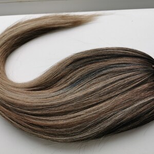 May include: A long, brown and blonde ombre hair extension with a brown elastic band.