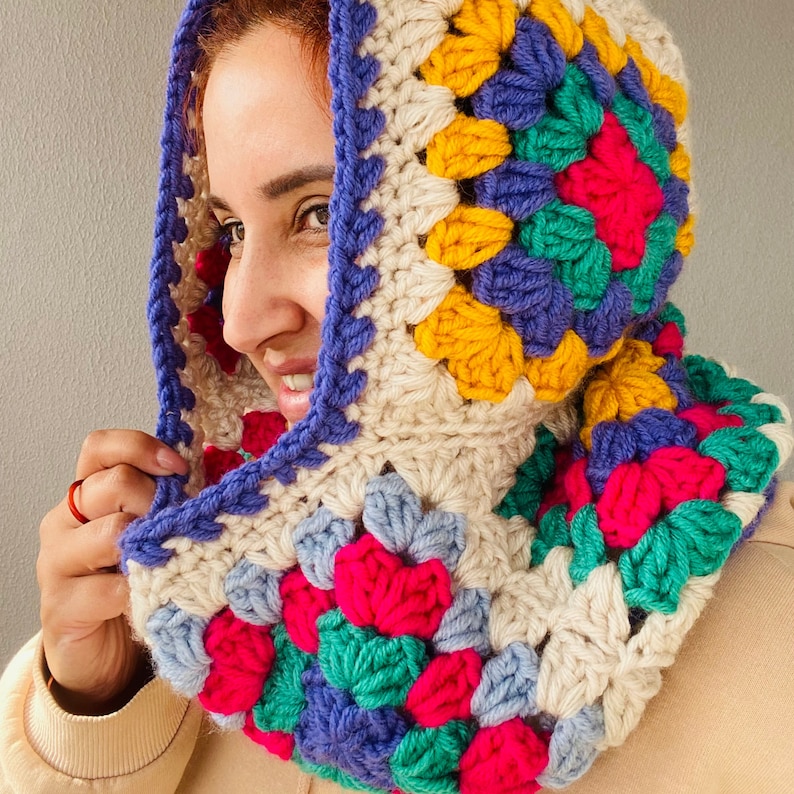 Puede incluir: Una colorida capucha de ganchillo con un patr&oacute;n de granny square. La capucha presenta una mezcla de colores vibrantes, incluyendo rosa, azul, amarillo, verde y crema. La capucha est&aacute; dise&ntilde;ada para ser usada alrededor del cuello y sobre la cabeza.