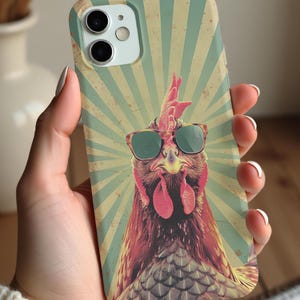 May include: A retro-style phone case featuring a rooster wearing sunglasses. The rooster is brown and red with a green background. The background has a vintage sunburst pattern.