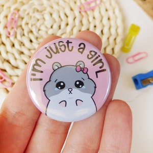 May include: Pink button with a cartoon hamster wearing a pink bow and the text "I'm just a girl".