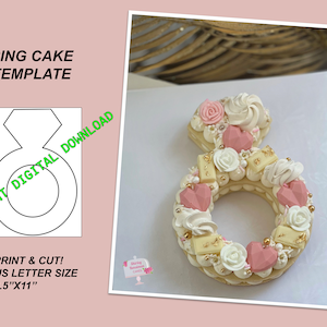 May include: Printable ring cake template for an 8.5" x 11" sheet of paper. The template shows a ring with a diamond shape on top. The template is for a cake that is decorated with pink and white frosting, flowers, and hearts.