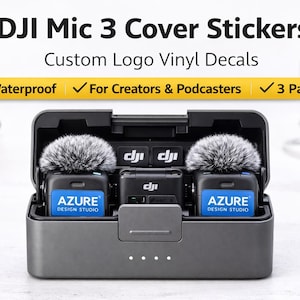 May include: A gray DJI Mic 3 charging case with two microphones, each covered with a fluffy gray windscreen. The case has the text "AZURE DESIGN STUDIO" on the front. The image also includes the text "DJI Mic 3 Cover Stickers" and "Custom Logo Vinyl Decals".