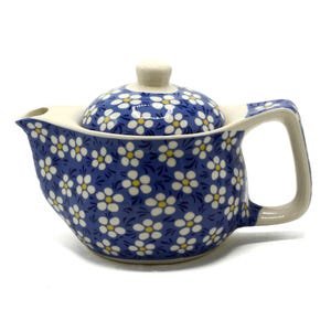 May include: A blue and white teapot with a floral pattern. The teapot has a lid and a handle.