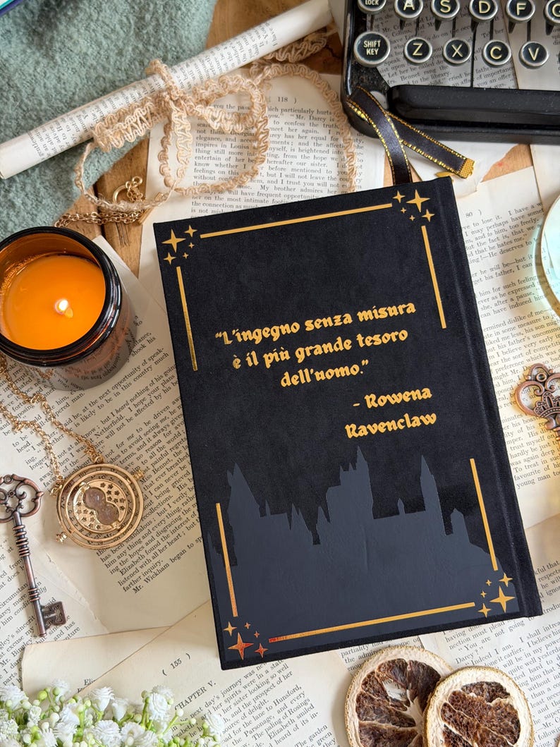 May include: A black book with gold accents and the quote "L'ingegno senza misura &egrave; il pi&ugrave; grande tesoro dell'uomo" by Rowena Ravenclaw. The book features a castle silhouette and star designs, with a lit candle and vintage accessories.