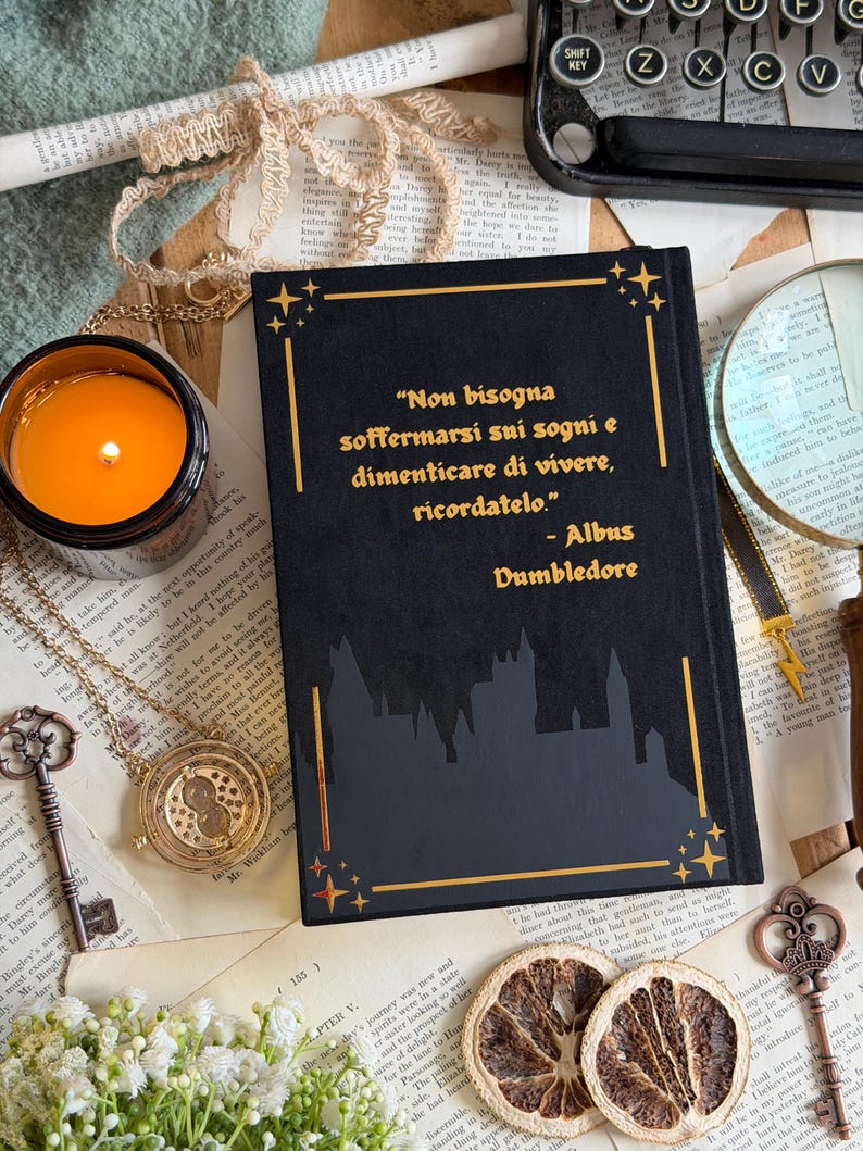 May include: A black book with gold lettering and a castle silhouette, featuring a quote by Albus Dumbledore. The image includes a lit candle, a necklace, keys, and dried orange slices, creating a vintage aesthetic.