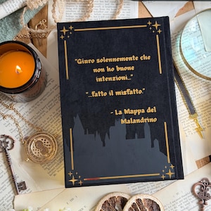 May include: A black book with gold lettering and a silhouette of a castle. The text reads "Giuro solennemente che non ho buone intenzioni... ...fatto il misfatto." and "La Mappa del Malandrino."