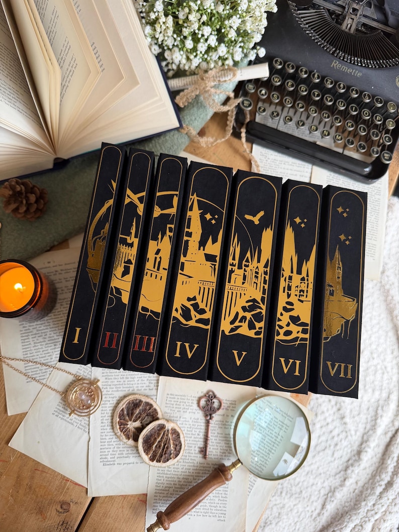 May include: A collection of seven black books with gold illustrations of a castle and Roman numerals I through VII. The books are arranged on a wooden surface with a magnifying glass, dried orange slices, and a vintage key.