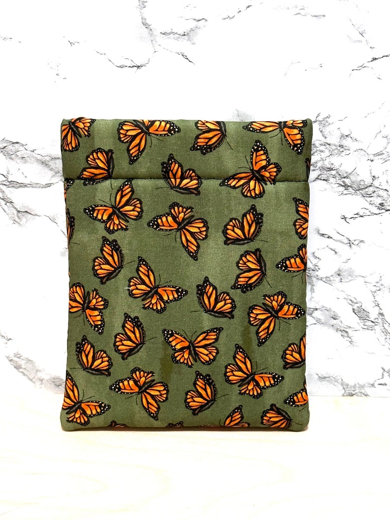 May include: A green fabric pouch with a zipper closure and a pattern of orange butterflies.