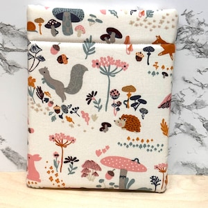 May include: A white fabric pouch with a woodland pattern featuring mushrooms, squirrels, hedgehogs, and other forest creatures. The pouch has a brown zipper and a white background.