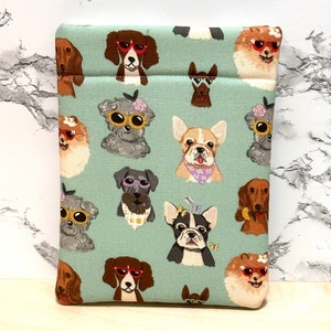 May include: A teal blue fabric pouch with a repeating pattern of dogs wearing sunglasses. The dogs are various breeds and colours, including a dachshund, a French bulldog, a Pomeranian, and a Schnauzer.