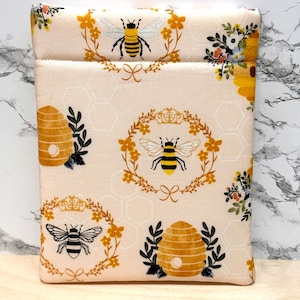 May include: A white fabric pouch with a bee and honeycomb pattern. The pouch has a zipper closure and is ideal for storing small items.