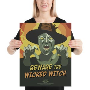 May include: Poster featuring a stylized illustration of the Wicked Witch from The Wizard of Oz. The witch is depicted with green skin, a black hat, and claw-like hands. The text "BEWARE THE WICKED WITCH" is prominently displayed in a vintage font.