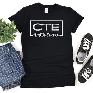 Peut inclure: T-shirt noir avec du texte blanc qui dit "CTE Health Science" dans un cadre.