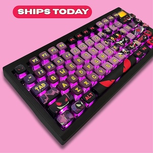 May include: Black mechanical keyboard with purple backlit keys. The keycaps are a mix of purple and black with white lettering and character designs. The keyboard has a black frame and a red and black design on the space bar.