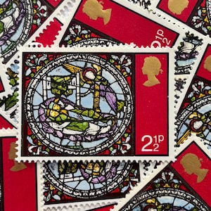 Può includere: Primo piano di francobolli britannici rossi. Presentano un profilo della regina Elisabetta II e il valore di 2,5 pence. Il francobollo centrale ha un disegno a vetrata entro una cornice circolare. Sfondo di francobolli.