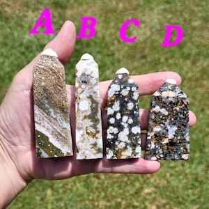 May include: Four polished stone towers with white tops. The towers are different colors and patterns, including brown, white, black, and green.