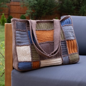 May include: A crocheted tote bag with a patchwork design in shades of brown, blue, green, and orange. The bag has two straps and is made with a variety of stitches.