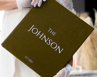 May include: A dark green linen-covered book with the text "THE JOHNSON EST 2024" printed in white.