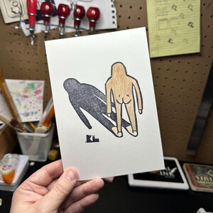 May include: A hand-drawn illustration of a person with a shadow. The person is brown and the shadow is black. The person is standing with their back to the viewer and their arms are at their sides. The shadow is slightly behind the person and is slightly larger than the person.