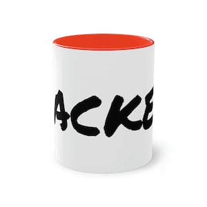 Può includere: Tazza in ceramica bianca con bordo rosso e la parola "HACKED" scritta in nero con tratti di pennello.