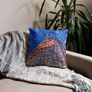 May include: A blue and red throw pillow with a vintage illustration of a roller coaster called "Cyclone" at Luna Park.