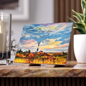 Puede incluir: Una impresión artística cuadrada del faro de Fire Island, Nueva York. La impresión presenta un paisaje colorido con un faro, campos de hierba y un cielo al atardecer. Las palabras "NEW YORK Fire Island Lighthouse" están impresas en amarillo.