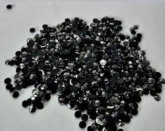 May include: A large pile of black rhinestones with a silver shimmer. The rhinestones are scattered on a white surface. The text "Night in Shining Armor" is written below the pile of rhinestones.