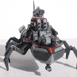 May include: A black and gray model of a futuristic spaceship with spider-like legs. The spaceship has a red stripe and a gray and black design.