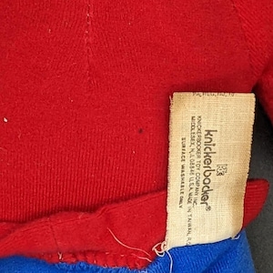 A red sweater with a label attached to it, which appears to be a knickerbocker toy.