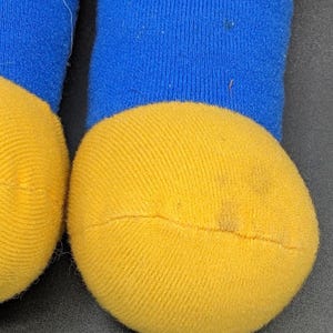 A close-up view of a pair of yellow and blue socks, with the yellow sock appearing slightly dirty.