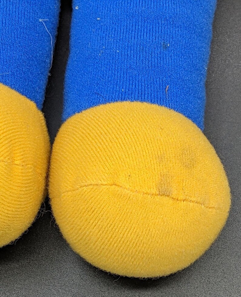 A close-up view of a pair of yellow and blue socks, with the yellow sock appearing slightly dirty.