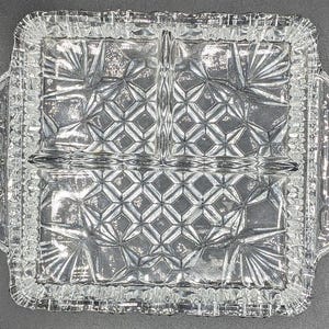 Peut inclure: Un plat de service divisé rectangulaire transparent avec un motif géométrique texturé. Le plat comporte trois compartiments et des poignées de chaque côté. Les bords sont festonnés, ajoutant une touche décorative à cette pièce de service vintage.