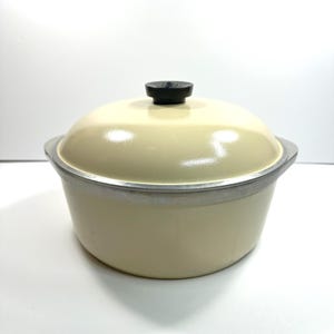 Peut inclure: Une marmite ronde de couleur crème avec un couvercle bombé assorti et un petit bouton circulaire noir sur le dessus. La marmite présente un bord argenté métallique sur le pourtour supérieur et une finition extérieure lisse et unie sur la base.