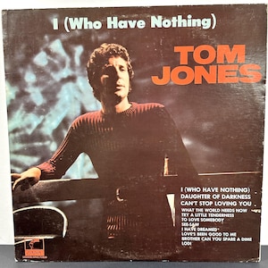 Può includere: Copertina dell'album vintage di Tom Jones, intitolata "I (Who Have Nothing)" in bianco, con il nome dell'artista in arancione. La copertina ha uno sfondo marrone scuro e una foto di Tom Jones. La tracklist è visibile sul lato destro.
