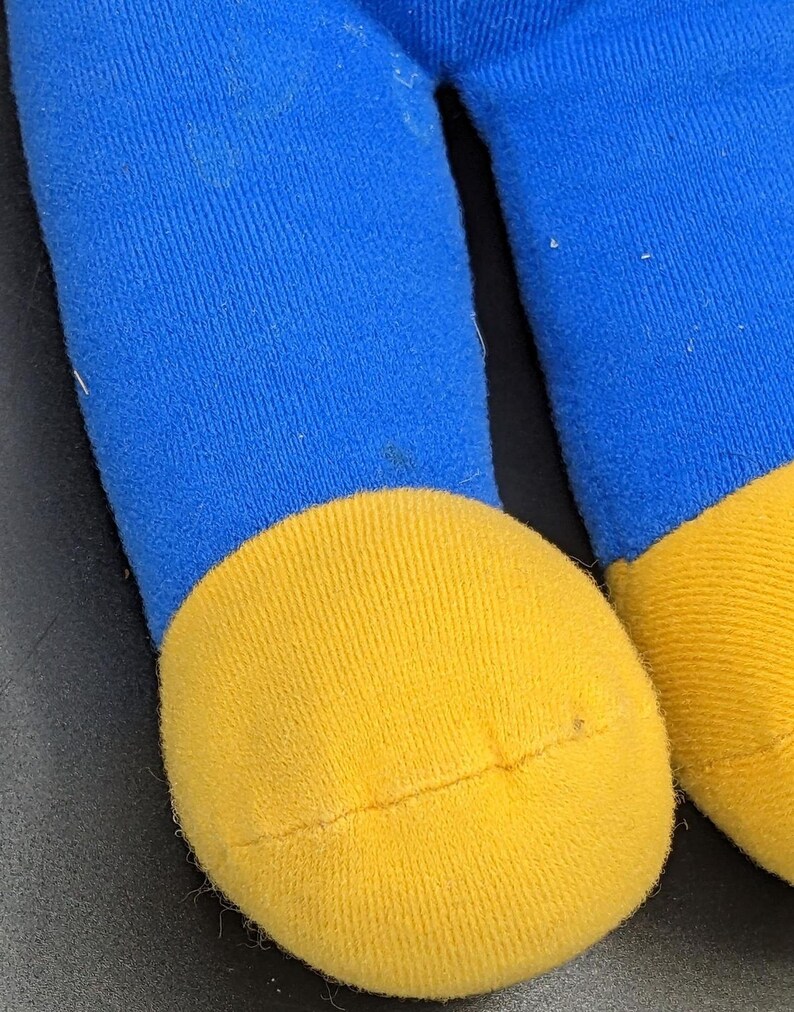 A close-up view of a blue and yellow toy, likely a stuffed animal, with a yellow sock and a blue sock visible.