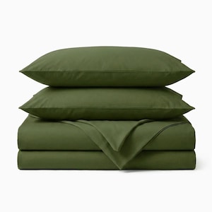 May include: A set of olive green bed sheets, including two pillowcases and a folded top sheet, stacked neatly. The sheets are made of a smooth, solid-colored fabric, creating a clean and minimalist aesthetic. The bedding set is designed for a standard bed.