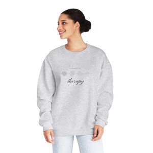 Puede incluir: Una sudadera gris con el texto "Normalizar la terapia" y un dibujo lineal de flores.