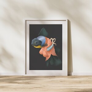 May include: A framed art print featuring a stylized goldfish with a blue head and dark body, adorned in a peach-colored garment with a pearl and blue accent. The artwork is set against a dark background.