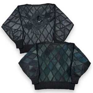 May include: A black and green patchwork sweater with a diamond pattern. The sweater has a unique design with a black and white graphic on the back.