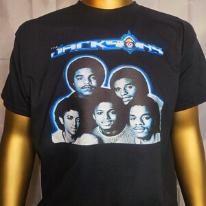 May include: Black t-shirt with a blue and white graphic of the Jackson 5. The graphic features a photo of the band members and the text "The Jacksons" in a blue and white font.