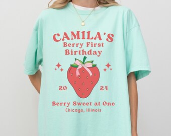 May include: A turquoise blue t-shirt with a strawberry graphic and the text "CAMILA'S Berry First Birthday Berry Sweet at One Chicago, Illinois".