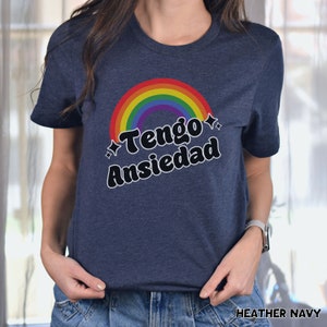 May include: A heather navy blue t-shirt with a rainbow arc and the text "Tengo Ansiedad" in black.