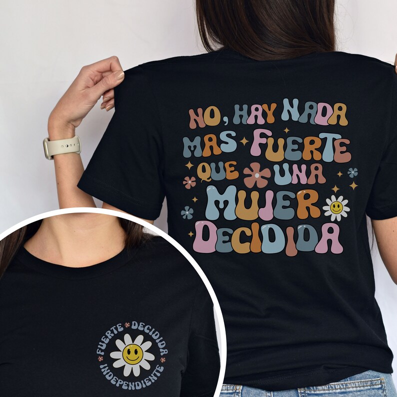 Pu&ograve; includere: Maglietta nera con una grafica retr&ograve; colorata che dice "NO, HAY NADA MAS FUERTE QUE UNA MUJER DECIDIDA". La grafica presenta fiori e un viso sorridente. La parte anteriore della maglietta ha una versione pi&ugrave; piccola della grafica con le parole "FUERTE DECIDIDA INDEPENDIENTE".