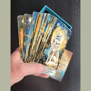 Hand holding fanned spread of Nature & Intuition Oracle Deck showing card variety and finish