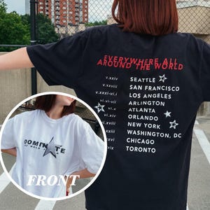 May include: Black graphic t-shirt with the text "EVERYWHERE ALL AROUND THE WORLD" in red. The shirt lists cities like Seattle, San Francisco, and Los Angeles. A smaller image shows a white t-shirt with the word "DOMINATE".