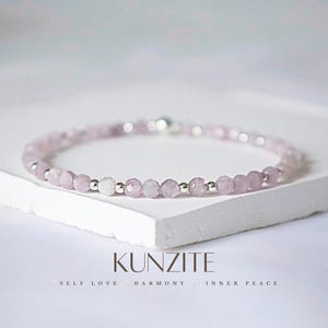 Puede incluir: Una delicada pulsera con pequeñas cuentas facetadas de kunzita rosa claro intercaladas con cuentas de color plateado. La pulsera se exhibe sobre una superficie blanca. La palabra "KUNZITE" está impresa en negro, junto con las palabras "SELF LOVE", "HARMONY" e "INNER PEACE".