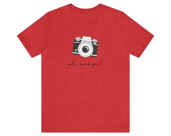 May include: Red t-shirt with a black and white illustration of a vintage camera and the text "oh snap!"