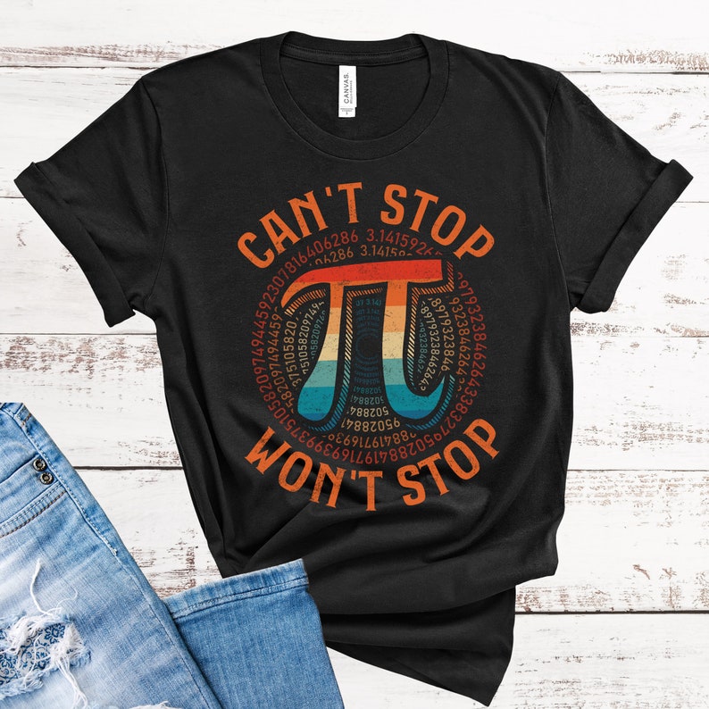 May include: A black t-shirt with a vintage-style graphic of the mathematical constant pi. The graphic features a rainbow color scheme and the text "CAN'T STOP WON'T STOP".