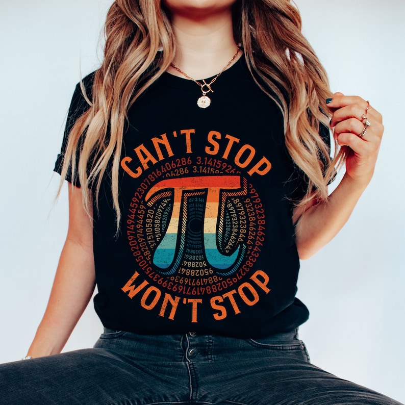 May include: A black t-shirt with a rainbow colored graphic of the mathematical symbol pi, surrounded by the digits of pi. The text "CAN'T STOP WON'T STOP" is printed below the graphic.